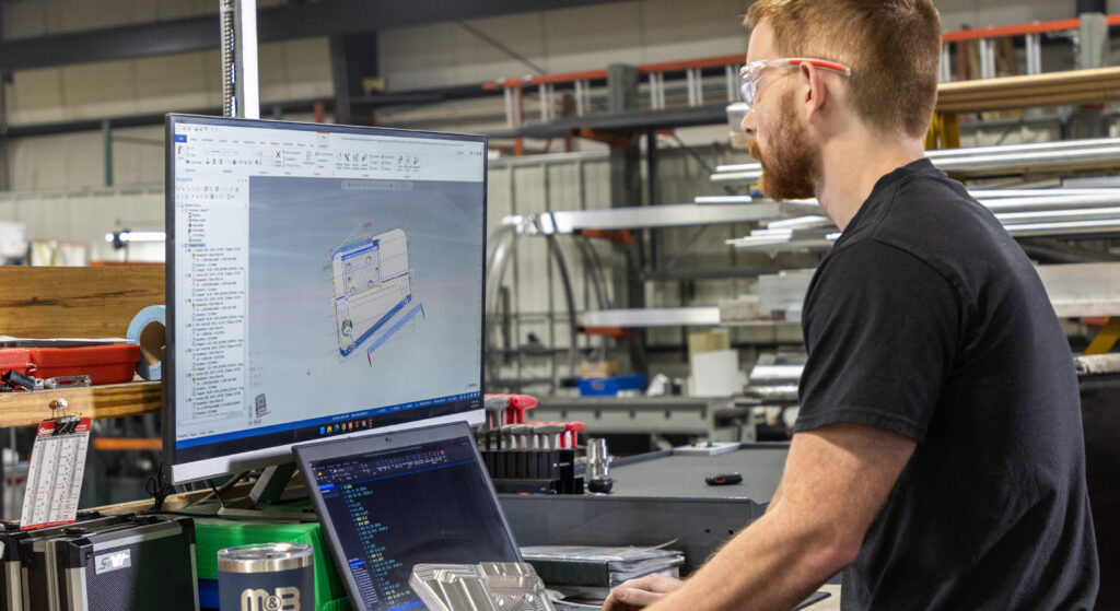 A man using a desktop computer to look at CAD drawings.