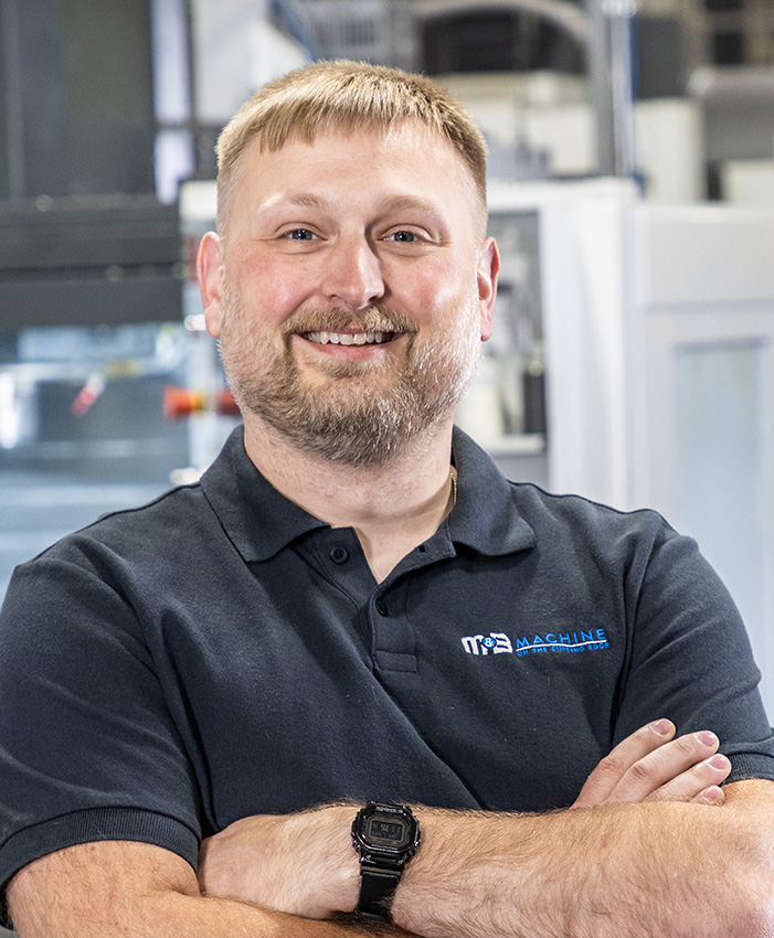 A picture of a man smiling and looking at the camera with crossed arms.