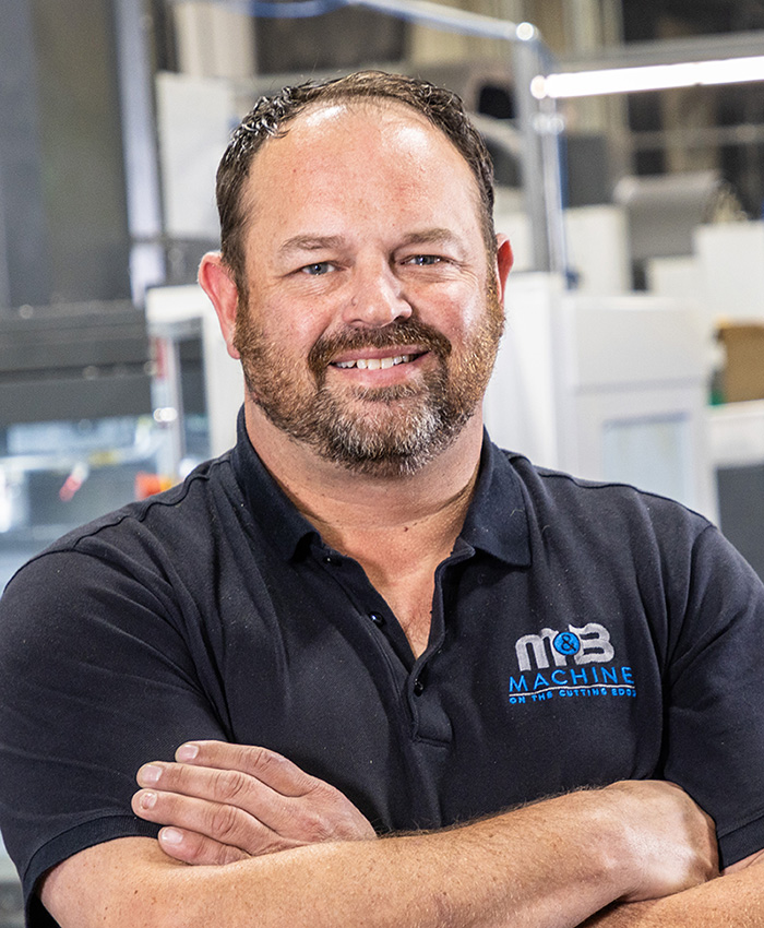 A picture of a man smiling and looking at the camera with crossed arms.
