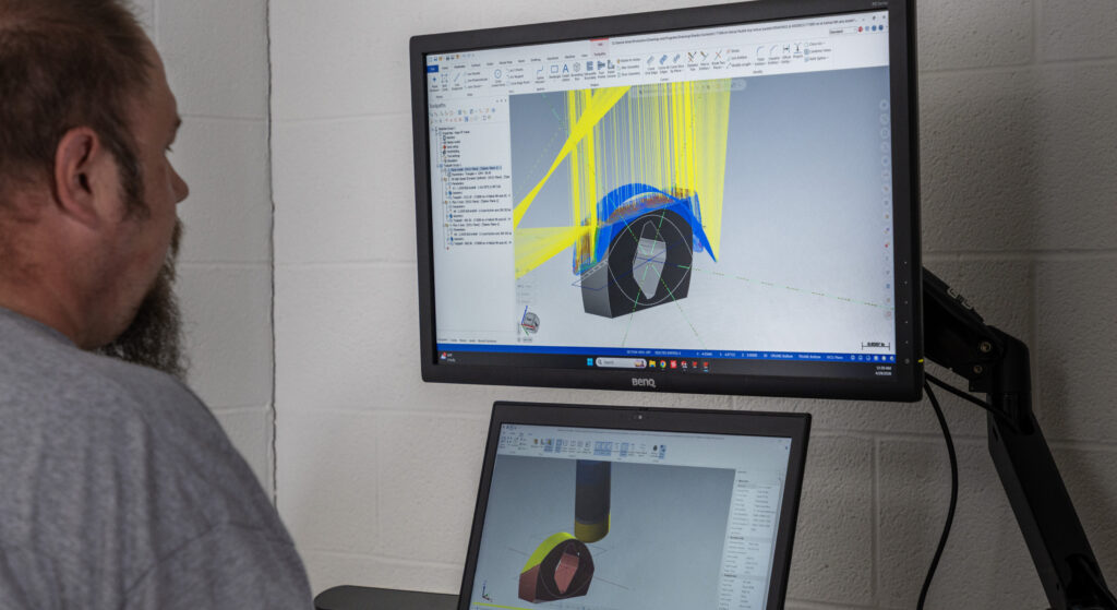 Looking over a man's shoulder onto a computer screen. The screen has a CAD drawing on it.