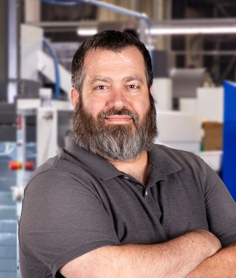 A picture of a man smiling and looking at the camera with crossed arms.